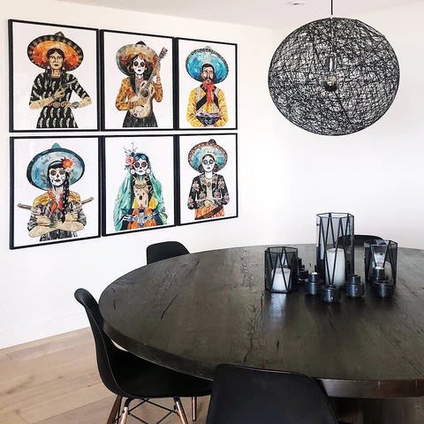 Set of six paper prints in frames showing figures with sugar skull makeup and Charro hats. Dia de los Muertos artwork for home.