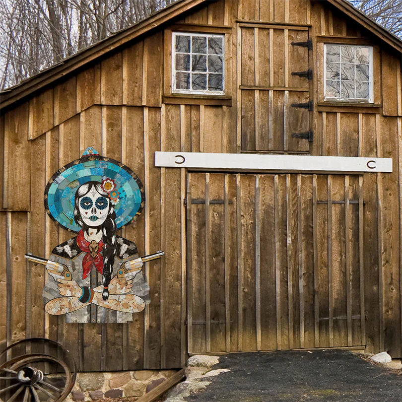 Large-scale cowgirl metal wall sculpture with sugar skull makeup hanging on a rustic barn. Art by Dolan Geiman.